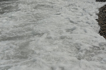 average waves on the sea reach the shore with foam and crash on the rocks with a noise