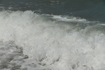 average waves on the sea reach the shore with foam and crash on the rocks with a noise
