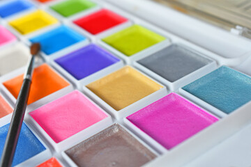 A close up image of a brand new water color paint set in a white plastic case. 