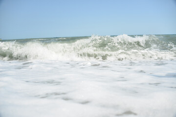 average waves on the sea reach the shore with foam and crash on the rocks with a noise