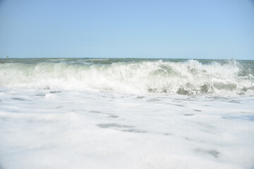 Naklejka na ściany i meble average waves on the sea reach the shore with foam and crash on the rocks with a noise