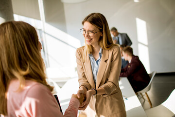 Young business women giving friendly handshake in the office