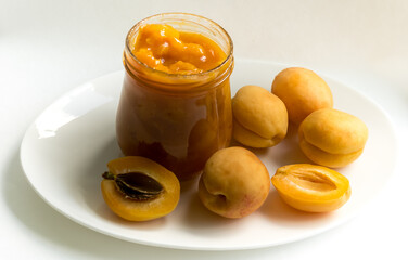 Apricot jam and apricots on a white plate