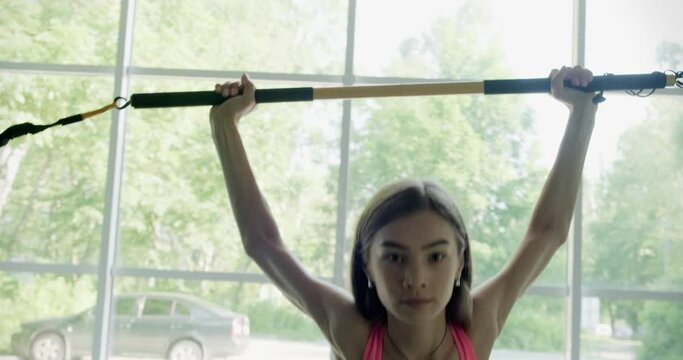 Beautiful young woman does training with weighted bar in gym. Attractive Female training
