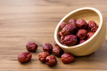 Dry red jujube or chinese dates fruit in wooden bowl isolated on rustic wood table background