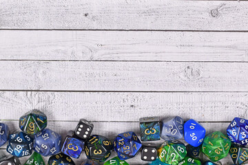 Roleplay game background with different blue and green RPG dices at bottom of wooden table...