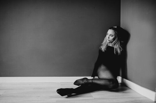 Skillfull modern dancer sitting on the parter in the dance studio. Contrast background.