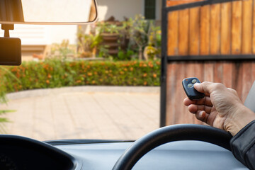 man inside red car, hand pressing remote control to open or close the electric sliding auto door.Home remote control, auto garage, security system in concept. 