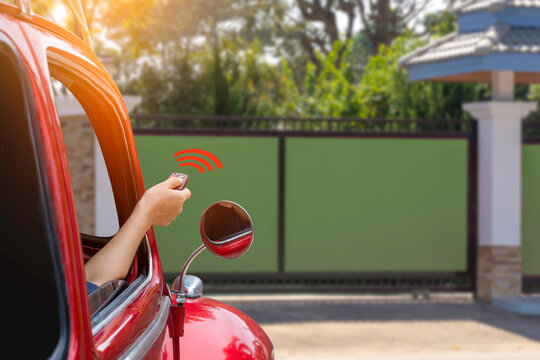 Woman inside red car, hand pressing remote control to open or close the electric sliding auto door.Home remote control, auto garage, security system in concept. 