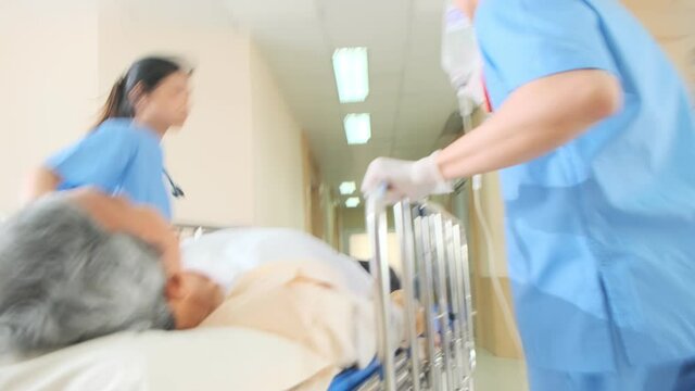Asian senior Patient laydown hospital bed pushed from surgeon team to emergency theatre. Nurse and doctor in a hurry taking patient to operation room health ideas concept