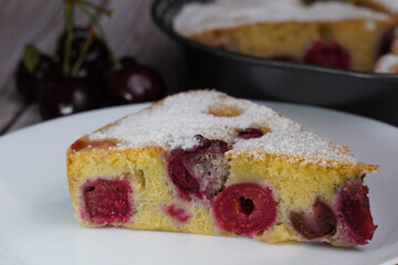 Piece of cherry pie with cherries in the left background