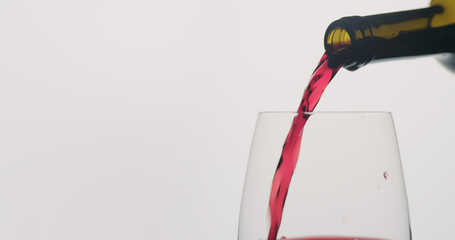 red wine pour into wineglass on neutral background