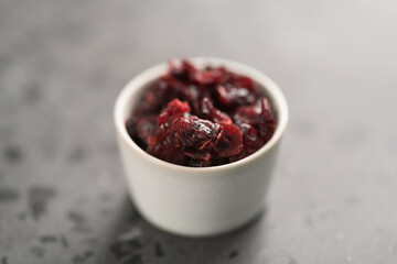 Dried cranberries in a bowl on concrete background