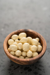 White chocolate or yogurt dragee with berries in olive wood bowl on concrete background