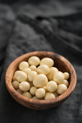 White chocolate or yogurt dragee with berries in olive wood bowl on linen background
