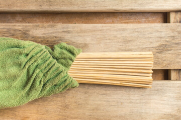 Bamboo broom wrapped in a green towel in a bath