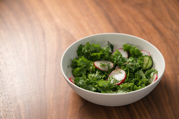 Summer fresh salad with radish, cucumber and herbs in white bowl