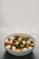 Salad with avocado, tomatoes and mozzarella in white bowl