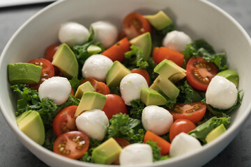 Salad with avocado, tomatoes and mozzarella closeup