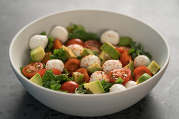 Salad with avocado, tomatoes and mozzarella in white bowl