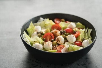 Salad with avocado, tomatoes and mozzarella in black bowl