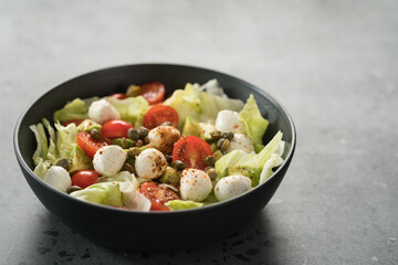 Salad with avocado, tomatoes and mozzarella in black bowl