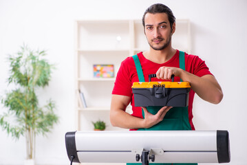 Young male contractor repairing heater indoors