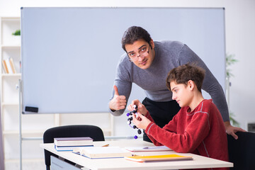 Fototapeta premium Young male teacher and schoolboy in the classroom