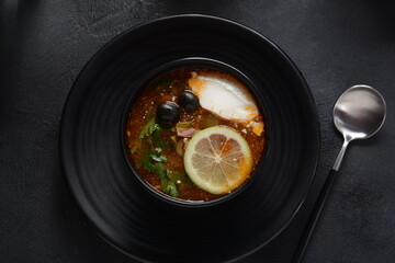 Russian traditional soup "Solyanka" with meat, sausages, salted cucumbers and olives.Soup in wooden bowl rustic style