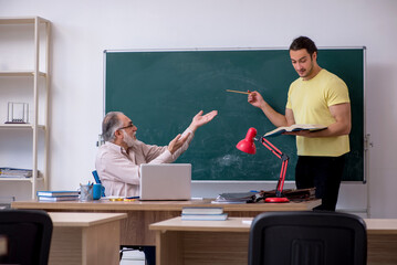 Old teacher and young male student in the classroom