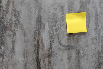 Blank yellow sticker note paper on cement background. Sticky note.