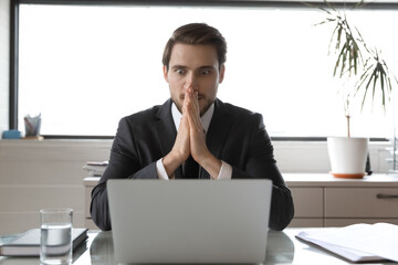 Stunned Caucasian male employee look at laptop screen shocked by unbelievable financial news on...