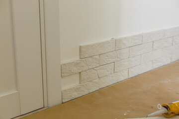 Professional Builder gluing decorative tile on wall. worker mounts decorative brick on wall
