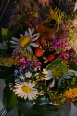 Bouquet of different forest flowers and berries (chamomile, forget-me-not, elecampane, hedge woundwort, raspberries) in a glass jar