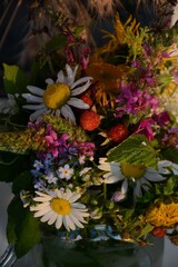 Bouquet of different forest flowers and berries (chamomile, forget-me-not, elecampane, hedge woundwort, raspberries) in a glass jar