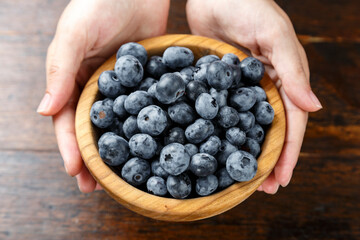 Blueberry in a wooden bowl held.