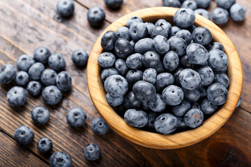 Freshly picked blueberries in wooden bowl on a wooden  table.