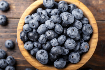 Freshly picked blueberries in wooden bowl on a wooden  table.