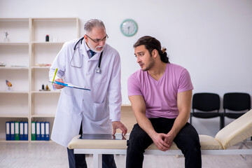 Obraz premium Young male patient visiting old male doctor
