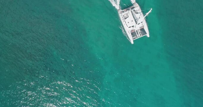Boat sails by in warm blue Hawaiian ocean water. Drone overhead top down aerial angle. 