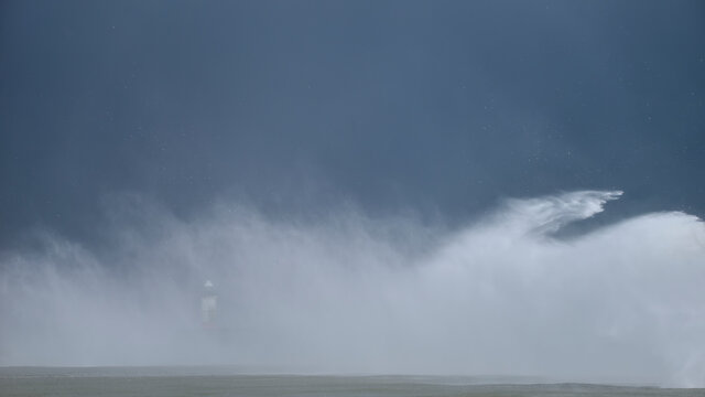 Massive waves crash over harbour wall onto lighthouse during huge storm on English coastline in Newhaven, amazing images showing power of the ocean © veneratio