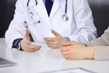 Unknown male doctor and patient woman discussing something while sitting in clinic. Best medical service in hospital, medicine, pandemic stop