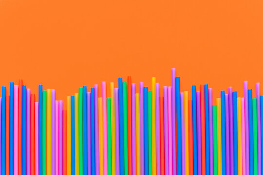 A strip of many plastic colored straws arranged in a row. Isolated