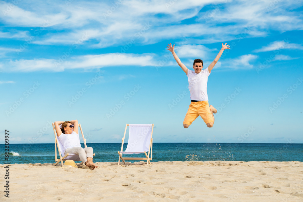 Wall mural Woman and man relaxing on beach