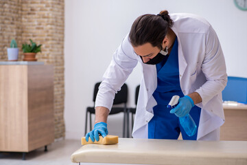 Young male contractor disinfecting clinic in pandemic concept