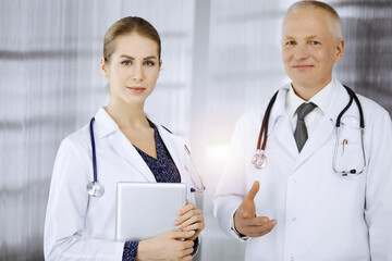 Elderly confident doctor and woman-physician discussing current disease therapy while standing in...
