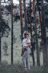 young woman walks in the forest, blonde with glasses