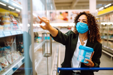 Young woman wearing face mask buying in supermarket. Shopping during the pandemic quarantine. Covid-2019.