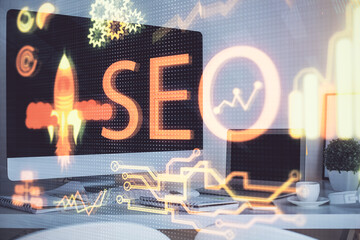 Multi exposure of table with computer and seo drawing hologram. Search optimization concept.