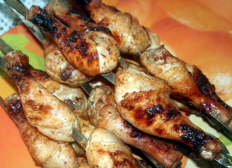 Charcoal-fried chicken shins strung on skewers closeup